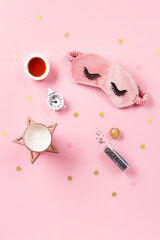 Cute sleeping mask, candle, lavender and alarm clock on pink pastel background, top view.