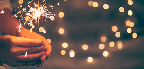 sparkler in the hands of a woman, christmas background, vintage colors