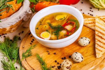 Soup with chicken meatballs, vegetable and quail eggs in white plate