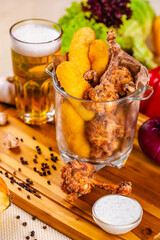Fish fingers and fried chicken in glass bowl served with beer
