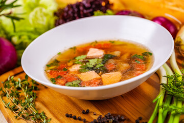 Soup with salmon, vegetables and spices in white plate