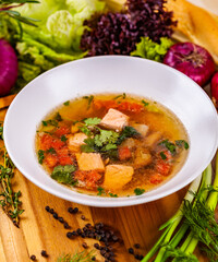 Soup with salmon, vegetables and spices in white plate