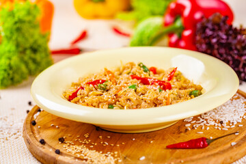 Rice with vegetables in white plate on wooden cutting board