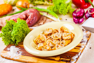 Dumplings with meat in beige plate on wooden board. Russian cuisine