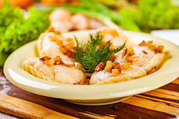 Vareniki with potatoes and mushrooms decorated with fried onion and dill