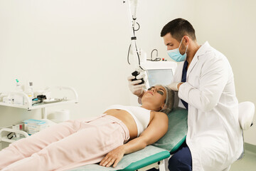 Doctor dermatologist and woman client during laser skin resurfacing treatment