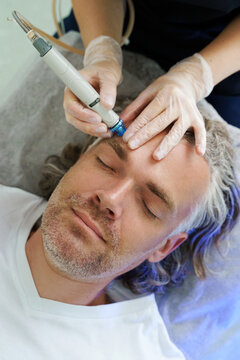 Middle aged man during deep facial cleansing in a cosmetology clinic