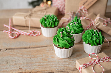 Christmas tree shaped cupcakes, surrounded with festive decorations and lights on the background
