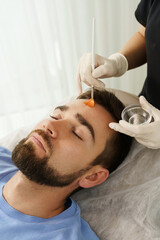 Obraz na płótnie Canvas Young man during peeling treatment in beauty clinic