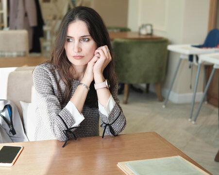 beautiful asian woman waiting for a waitor in a cafe and looking aside. brinette woman thinking and sitting alone