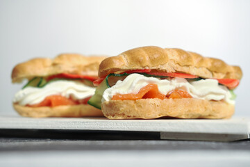 two Snack eclairs profiteroles with creamcheese, cucumber and smoked salmon red fish on white table. tasty appetizer, holiday lunch, weekend menu