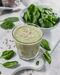 Glass of homemade healthy green smoothie with fresh baby spinach