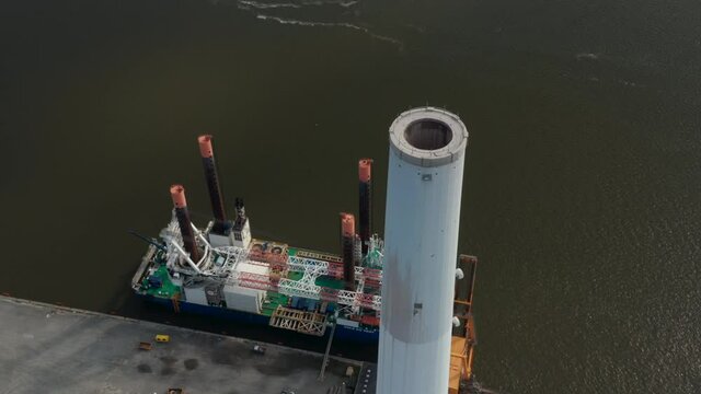 Aerial view of the chimney of Esbjerg Power Station in Denmark. Drone view revealing Liebherr Seafox 5, the biggest offshore crane moored at harbour
