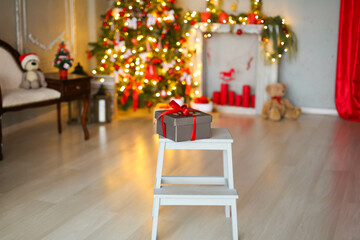 Christmas box with a gift tied with a ribbon on the background of a Christmas tree