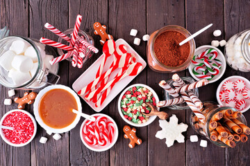 Christmas hot chocolate bar with a mixture of sweet toppings. Top view table scene on a dark wood...