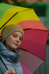 On an autumn rainy day, a teenage girl stands under a bright rainbow umbrella. Omsk, Omsk Oblast, Russia
