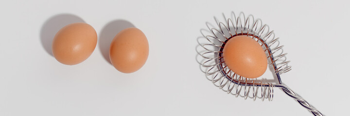 Three eggs and stainless steel Wire Whisk on white background