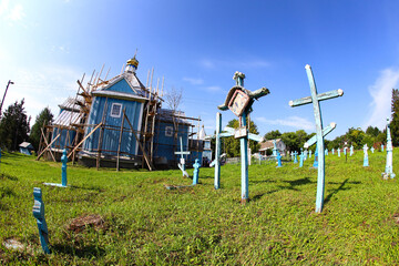 Fototapeta na wymiar Ternopil region Ukraine, August 2021, Church cemetery of wooden and stone blue crosses, reconstruction of the old church. The concept of Orthodoxy.