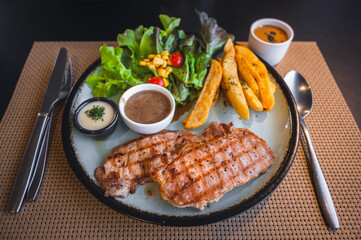 Grilled pork steak and pepper sauce with french fries and salad.