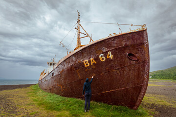 Girla at the shipwreck of BA 64 on a beach in Patreksfjordur (Patreksfjörður)at the Westfjords is...