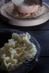 Thin shavings of Swiss elite tete de moine cheese. Special girolle knife for slicing cheese out of focus.Vertical photo on a black background.