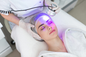 Obraz na płótnie Canvas Ultrasonic massager. Light skin treatment, the woman in the beauty salon