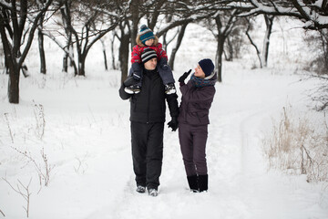 Fototapeta na wymiar Family Walking Through Snowy Woodland
