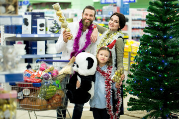 Happy young family in the supermarket chooses gifts for the new year