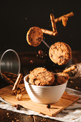 Chocolate cookies on dark background with falling elements