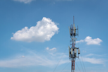 Telecommunication tower and its wireless cellular transmission antenna in blue sky and white cloud background. Mobile phone network transmitter technology and telephone communication concept.