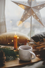 Christmas star, cup of tea, lights, trees, candle at window. Scandi Winter hygge. Merry Xmas