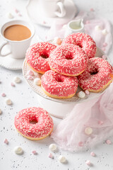 Delicious and homemade pink donuts and coffee as perfect snack.