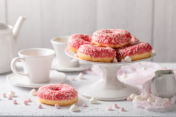 Homemade and sweet pink donuts and coffee topped with sprinkles.