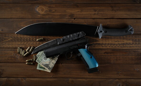 Pistol 9 mm, handgun semi-automatic, bullets, knife and machete on wooden planks, boards, table background, top view