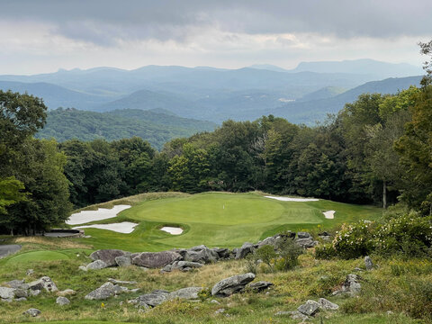 Spectacular par 3 hole on a mountain golf course with mountains in the background