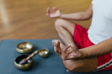 Close-up hands of a man meditating on yoga mat. Relaxation and meditation. Tibetan singing bowls.
