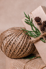 Decoration gifts in eco-style.Gift boxes are wrapped in craft paper,tied with cotton thread,decorated with thuja leaves,alder cones and burlap, close-up.Christmas,New Year and eco-friendly concept.