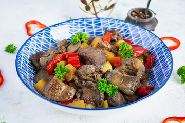 Delicious fried chicken liver with pepper, apples and herbs on light wooden background