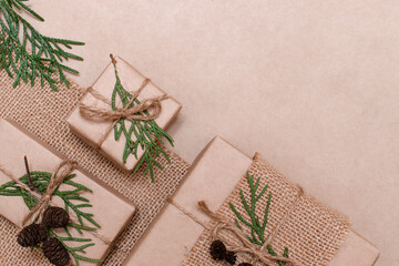Decoration of gifts in eco-style.Gift boxes are wrapped in craft paper,tied with cotton thread,decorated with thuja leaves,cones and burlap.Christmas,New Year and eco-friendly concept,copy space.