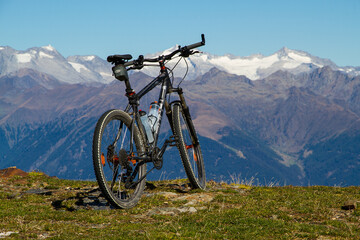 A black mountainbike parked on a mountain summit with a great and clear view to the surrounding landscape