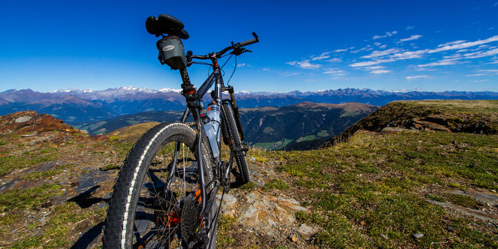 A black mountainbike parked on a mountain summit with a great and clear view to the surrounding landscape