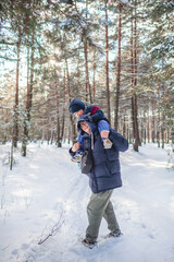 Fototapeta na wymiar Happy single dad carries his little son on shoulders so that he can reach the branch and shake snow off the tree, active weekend, seasonal outdoor activities, family lifestyle, true moment