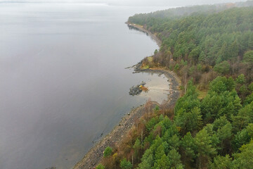 Fototapeta na wymiar Karelia, Onega Lake, Petrozavodsk Bay. Aerial photography showing the forest and the coast, near the botanical garden. The water surface of the lake and the autumn forest. Vacation in Russia concept.