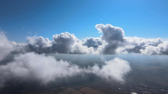 Aerial view from airplane window at high altitude of earth covered with puffy cumulus clouds forming before rainstorm.