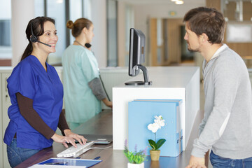 Obraz premium male patient talking to nurse at reception desk in hospital