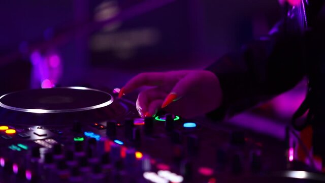 Girl dj playing techno music in night club. Female disc jockey plays electronic musical tracks on rave party in nightclub using professional sound mixer and cd turntables