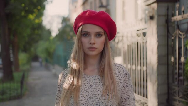 Elegant young attractive caucasian woman in red beret looking at camera outdoors. Beautiful stylish lady on autumn street. Fashion model.