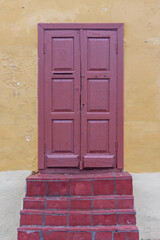 Fototapeta premium Red door on the background of a yellow wall