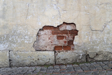 Very old brick wall with a collapsed patch of plaster