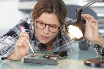 female computer technician directing lamp onto electronic component